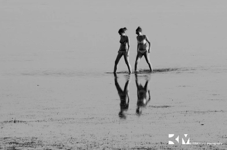 two women walk on the beach in black and white