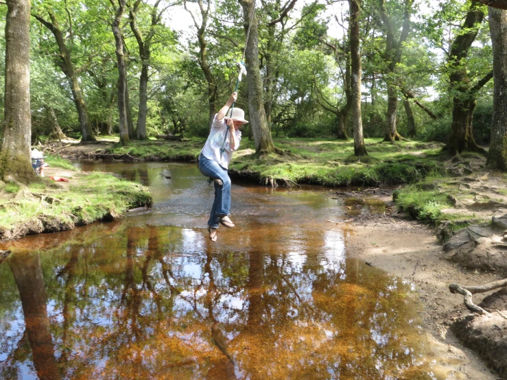 man standing in water throwing frisbees from a stream