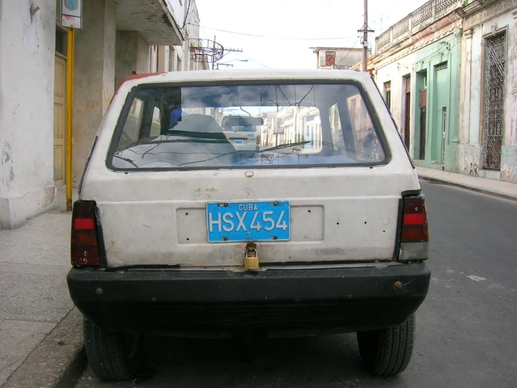 the rear end of a white hatchback car on a city street