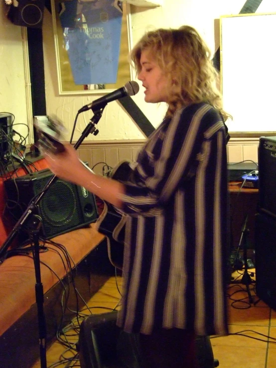 a woman with a microphone singing into some mic stands