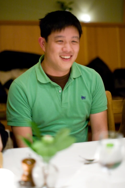a smiling young man sitting at a table in front of a plate