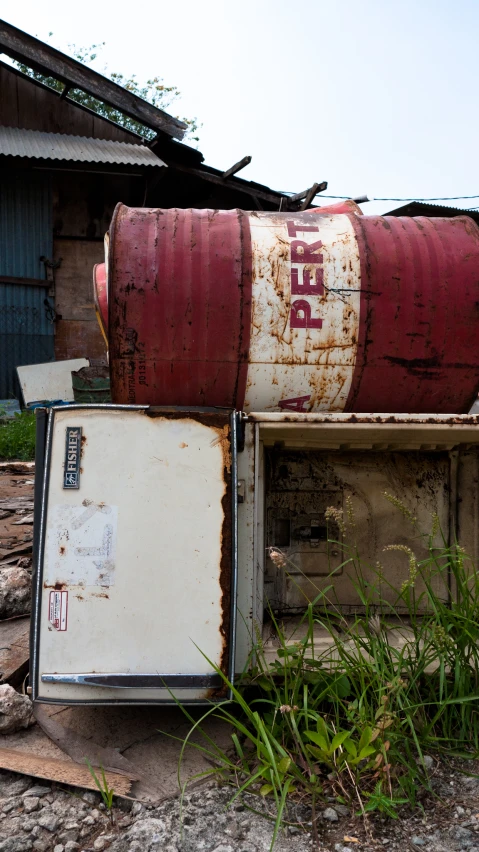 a broken refrigerator with a gas can wrapped around it's top