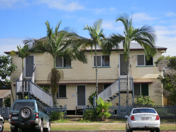 the street is lined with palm trees and two cars parked along the curb