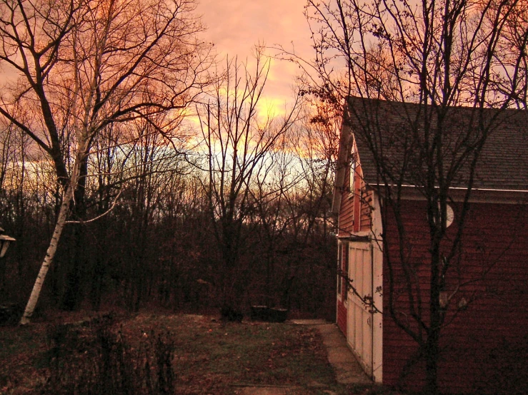 there is an orange sky with clouds over the trees