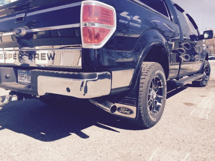 the back end of a black truck with two metal spoke wheels