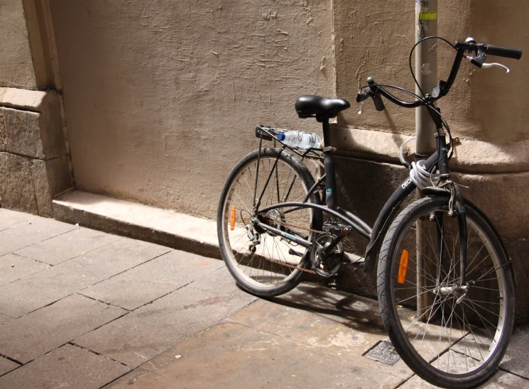 a bicycle parked next to a wall in the sunlight