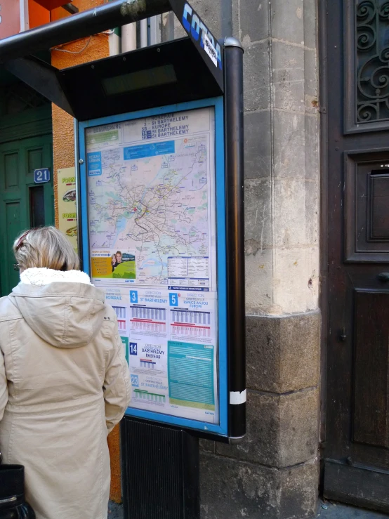 a woman is standing on the sidewalk and looking at the map