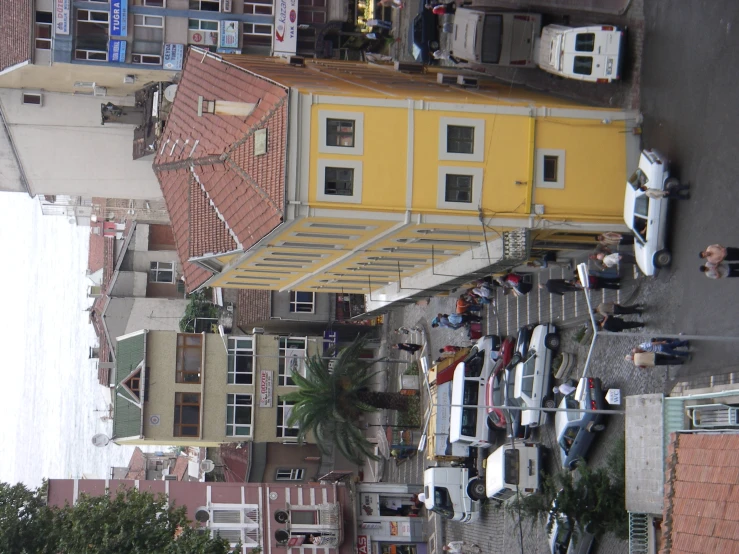 an aerial view of a neighborhood with yellow buildings and white cars
