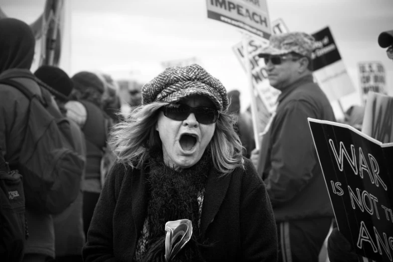 a protester is yelling in front of the camera with others holding signs