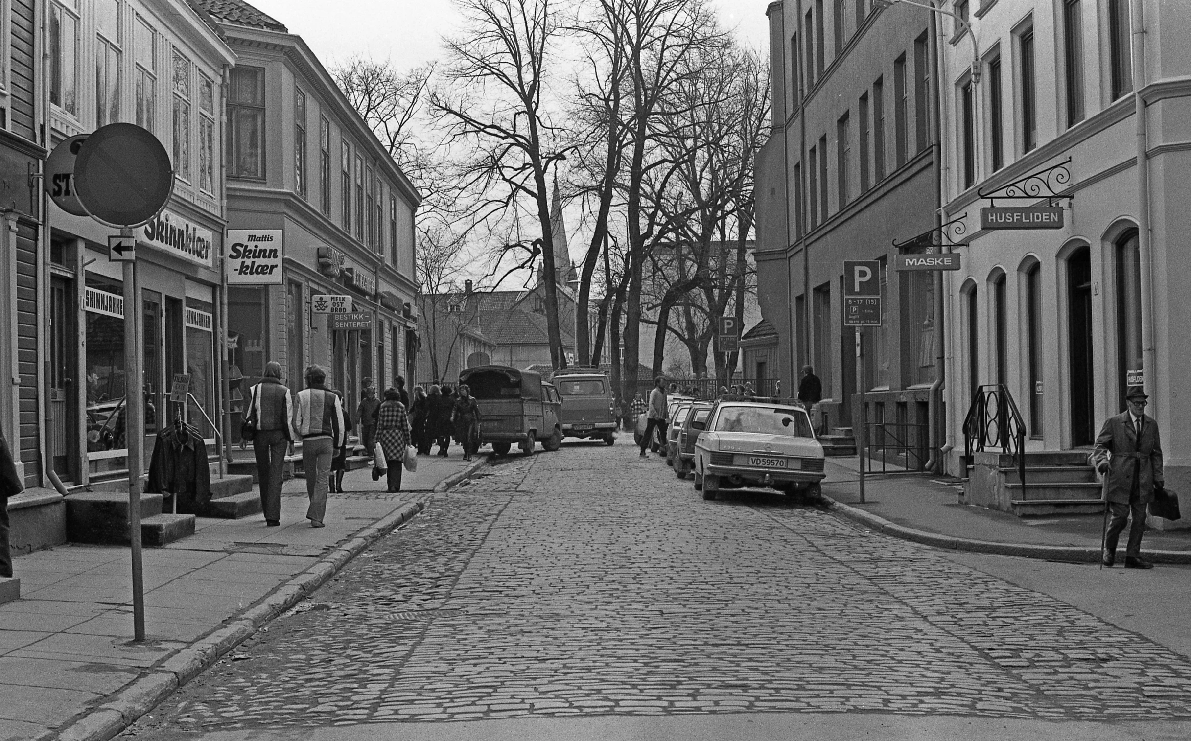 people and vehicles on a bricked road in black and white