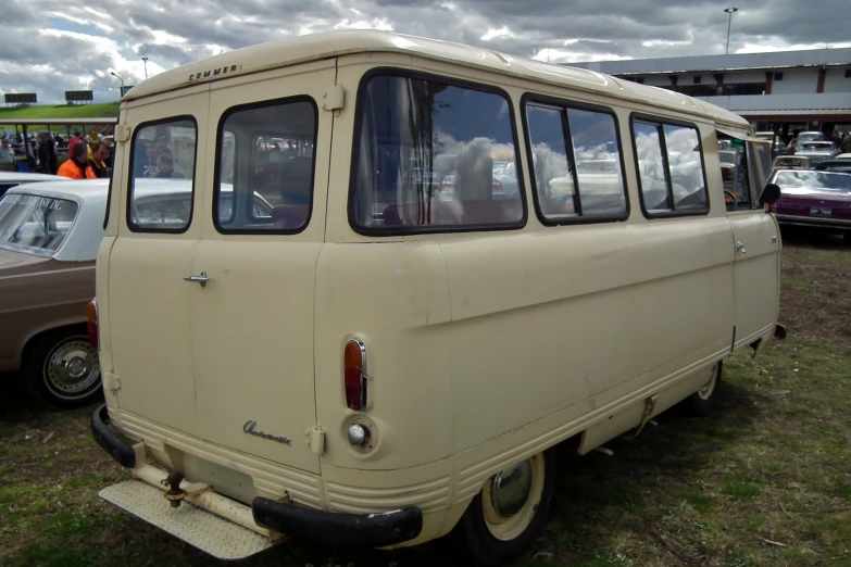 an old, tan van sits in the grass and looks like it is used as an rv