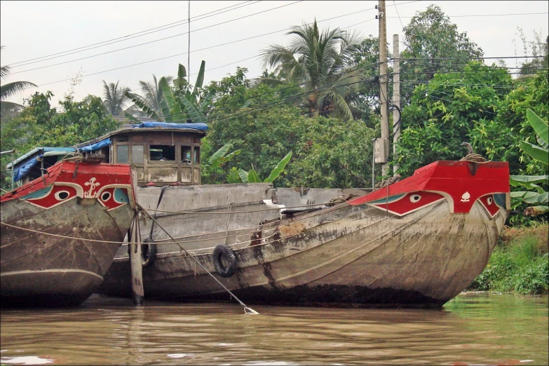 three brown boats docked at the side of a river