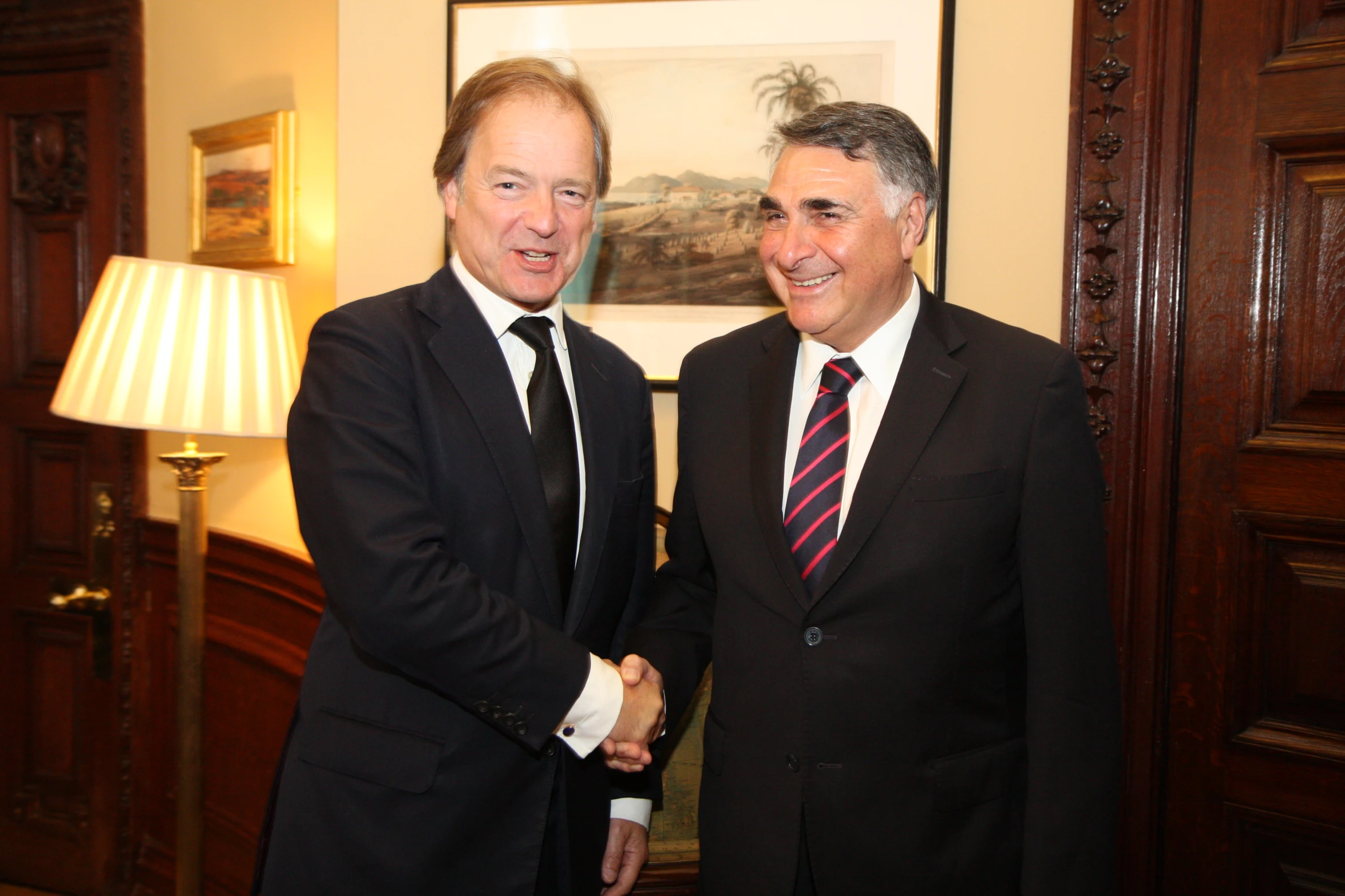 two men in suits shaking hands in an ornate room