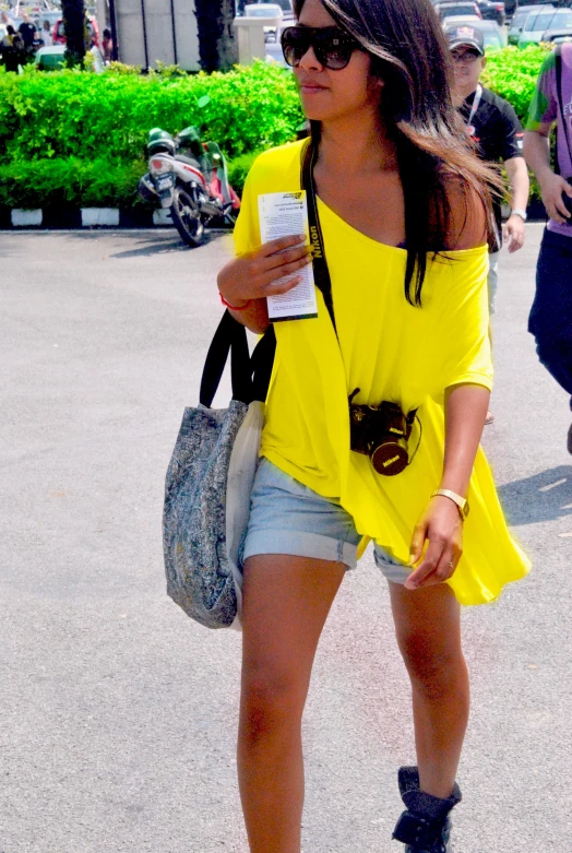 a woman walking down the street carrying a purse and holding a cup