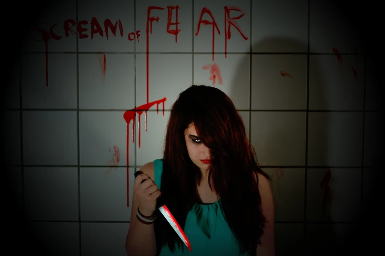 a woman with long hair holding a knife in front of a tiled wall