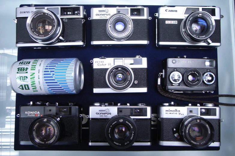 many cameras sit beside each other next to a soda can