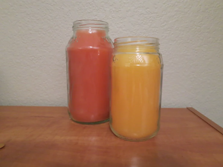 two jars containing orange and orange liquid sit on a table