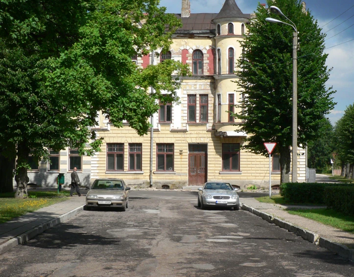 the buildings are very old and have two cars parked in front