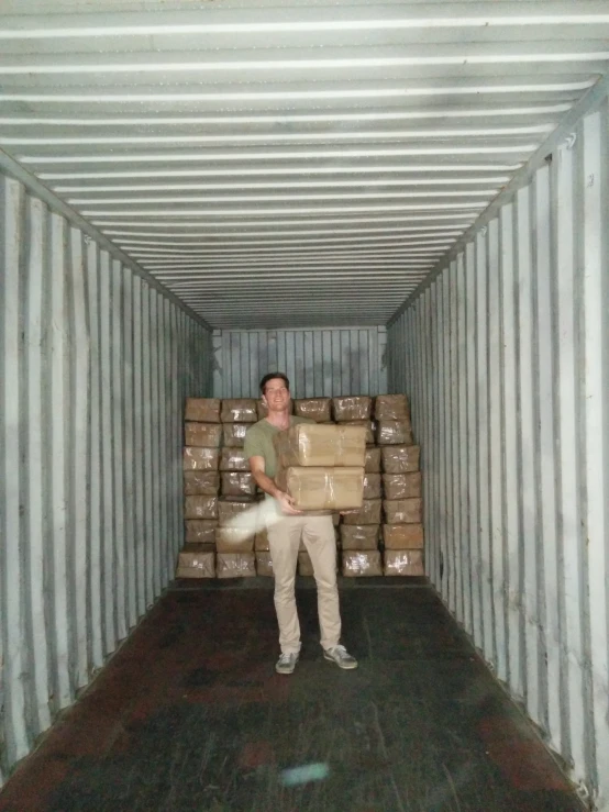 a man standing next to a big pile of cardboard boxes