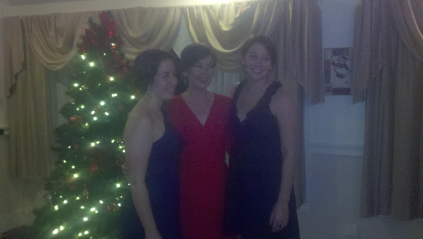 two women standing next to a christmas tree