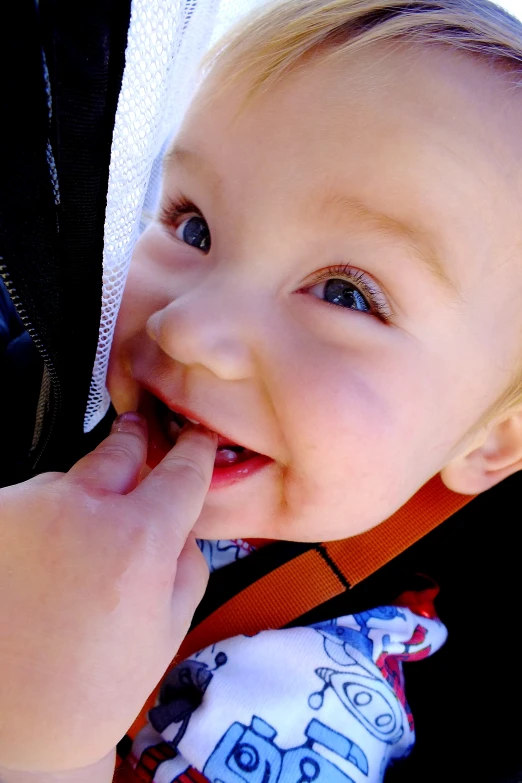 the young child is smiling and putting his finger up to his mouth