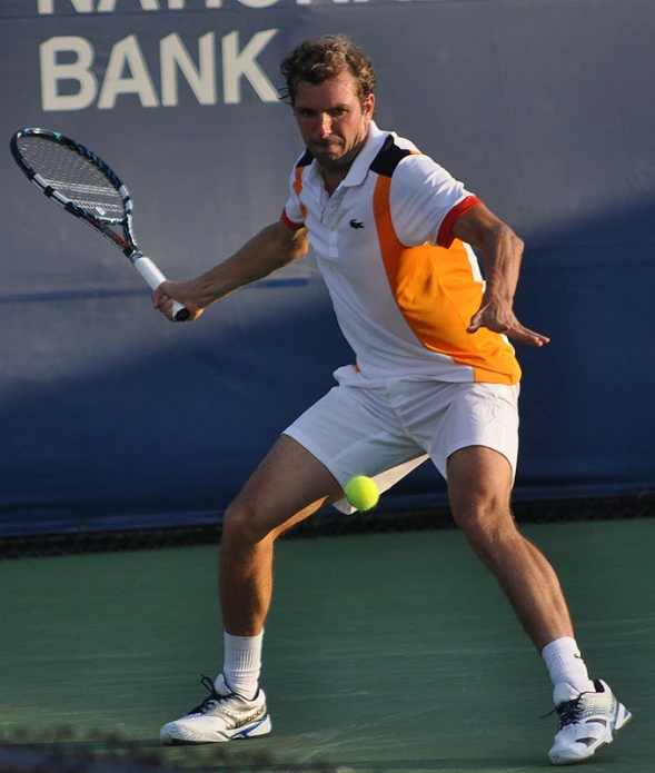man in all white and yellow holding a racket