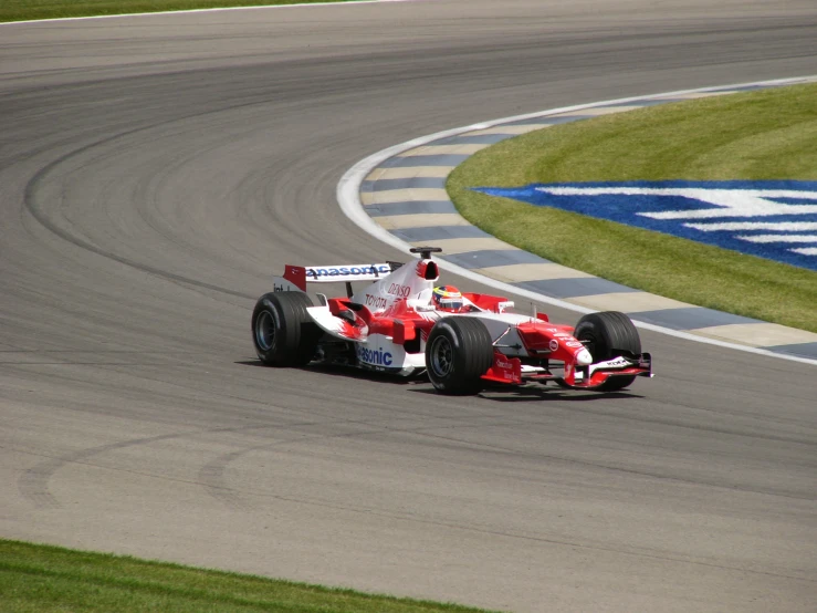 a red and white racing car speeds down the track