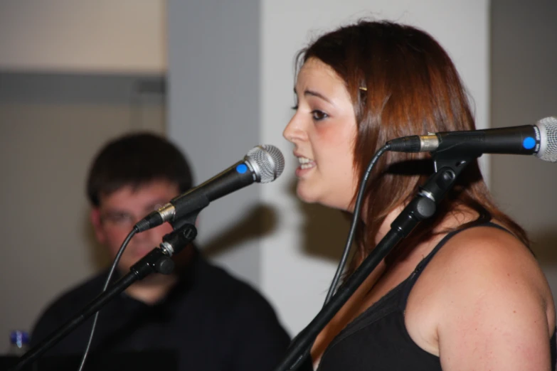 the woman is singing with two microphones on her shoulders