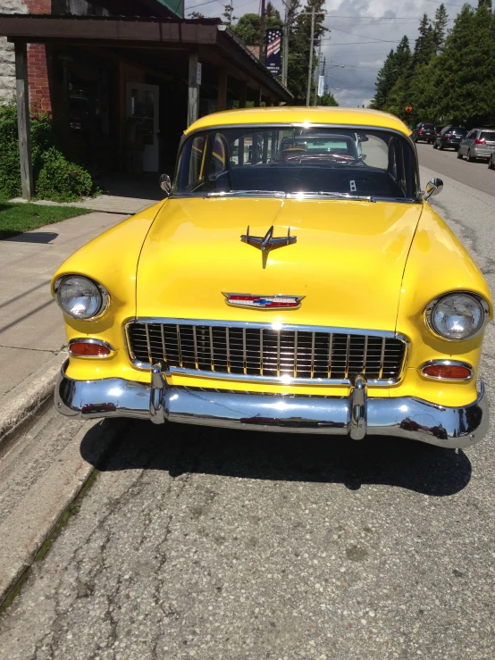 an old yellow car parked on the side of a road