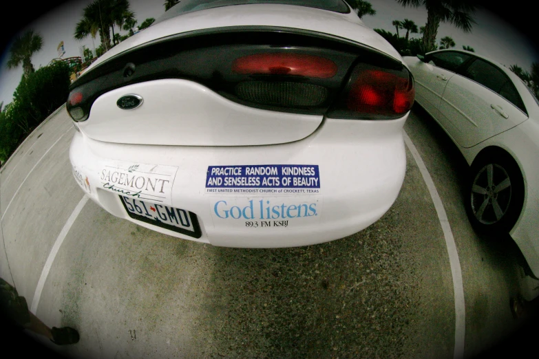 the back end of a white car with a bumper sticker attached
