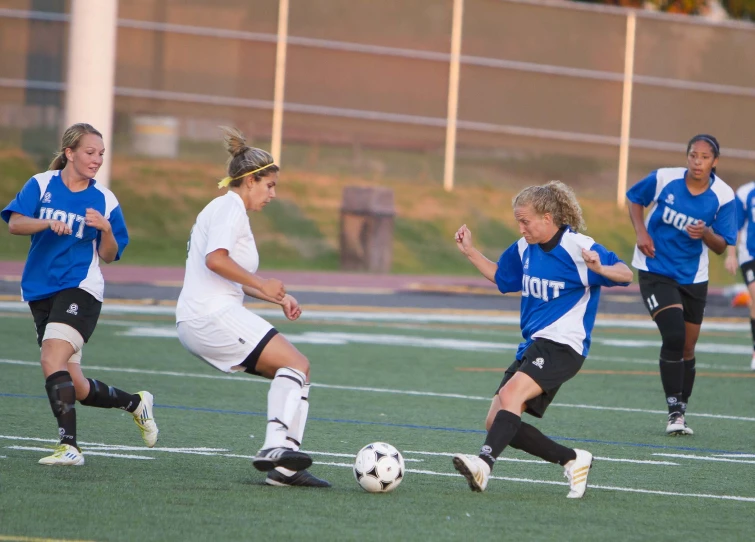 young ladies are playing soccer on a field