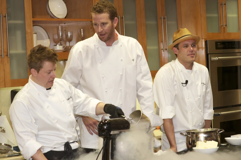 three men are cooking with a large steam stove