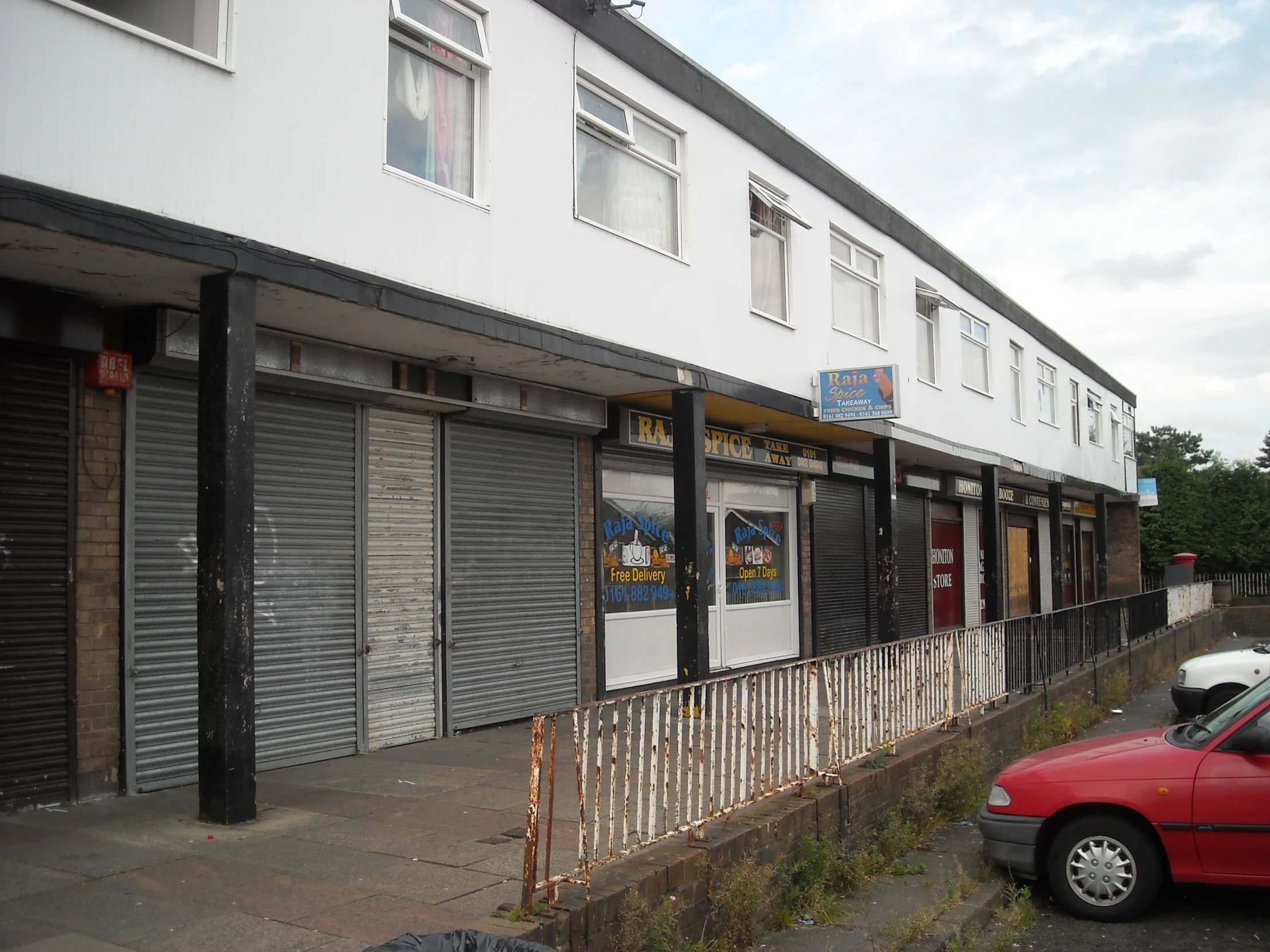 a small red car parked next to a closed down shop