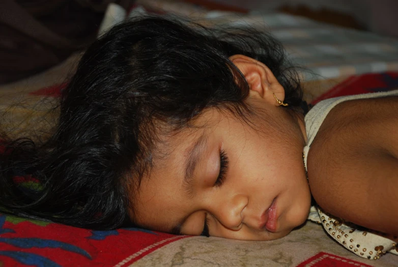 a child lying in the bed and snuggling her head