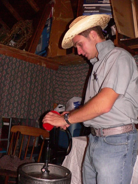 a man in a cowboy hat standing over a metal barrel