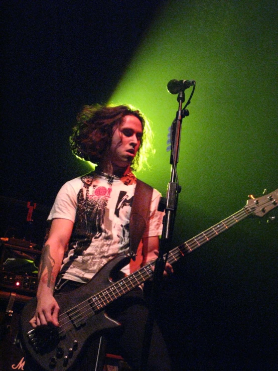 a man with long hair and piercings holding a bass