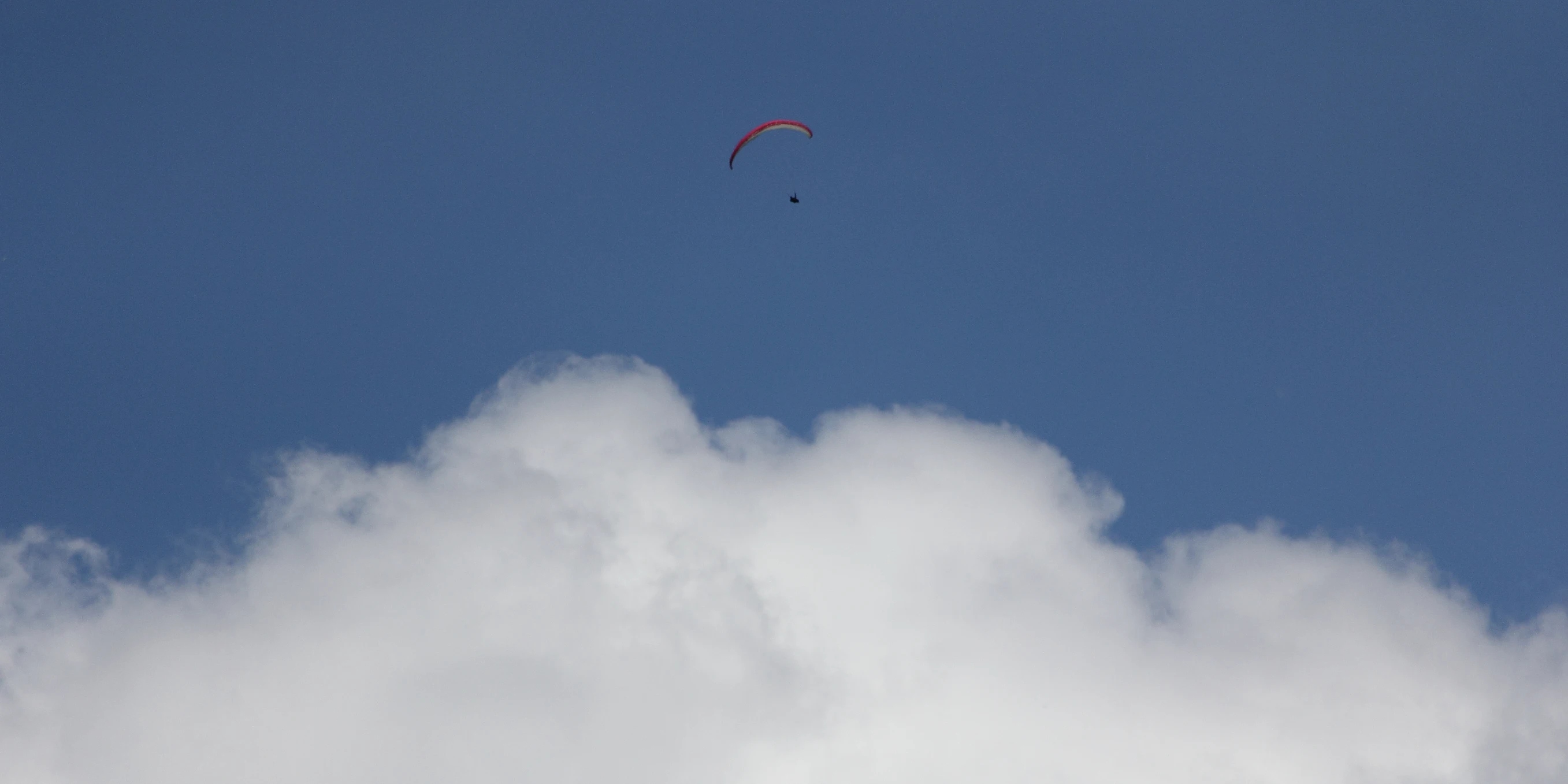 a para - sailer is flying through the cloudy sky