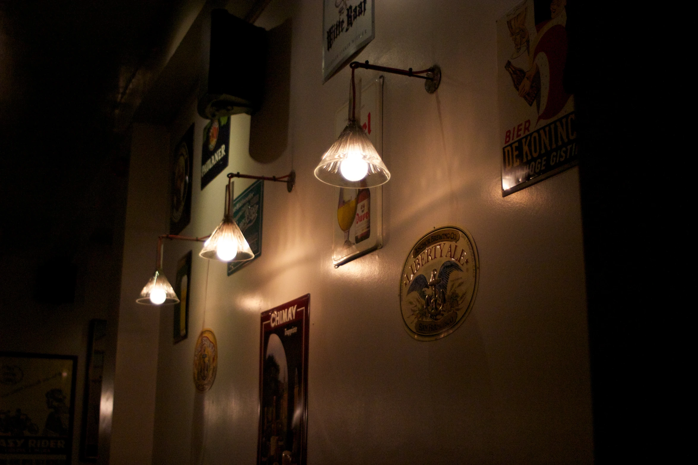 a dimly lit room with two wall lamps and posters