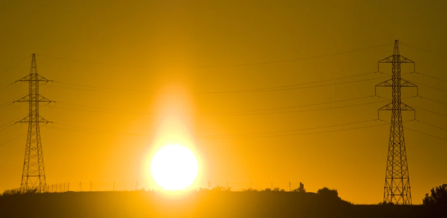 the sun is setting in front of power lines