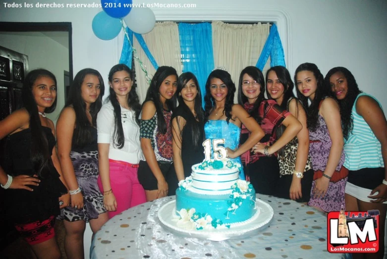 a group of young women posing around a cake