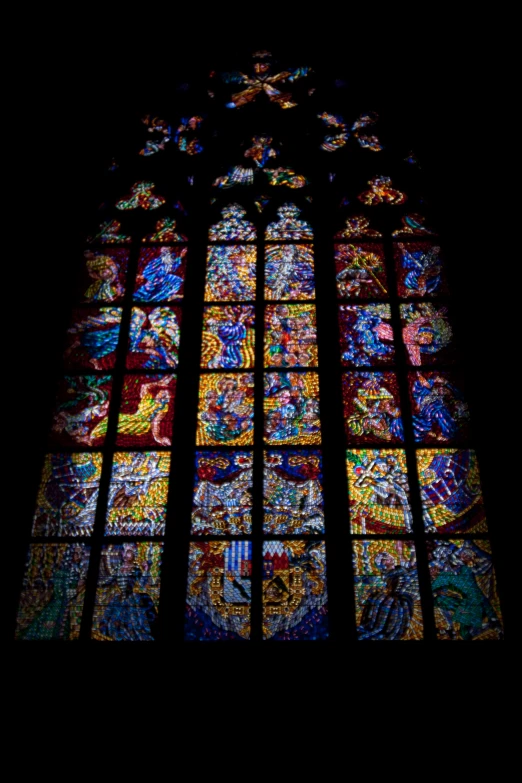 a multi colored stained glass window is illuminated