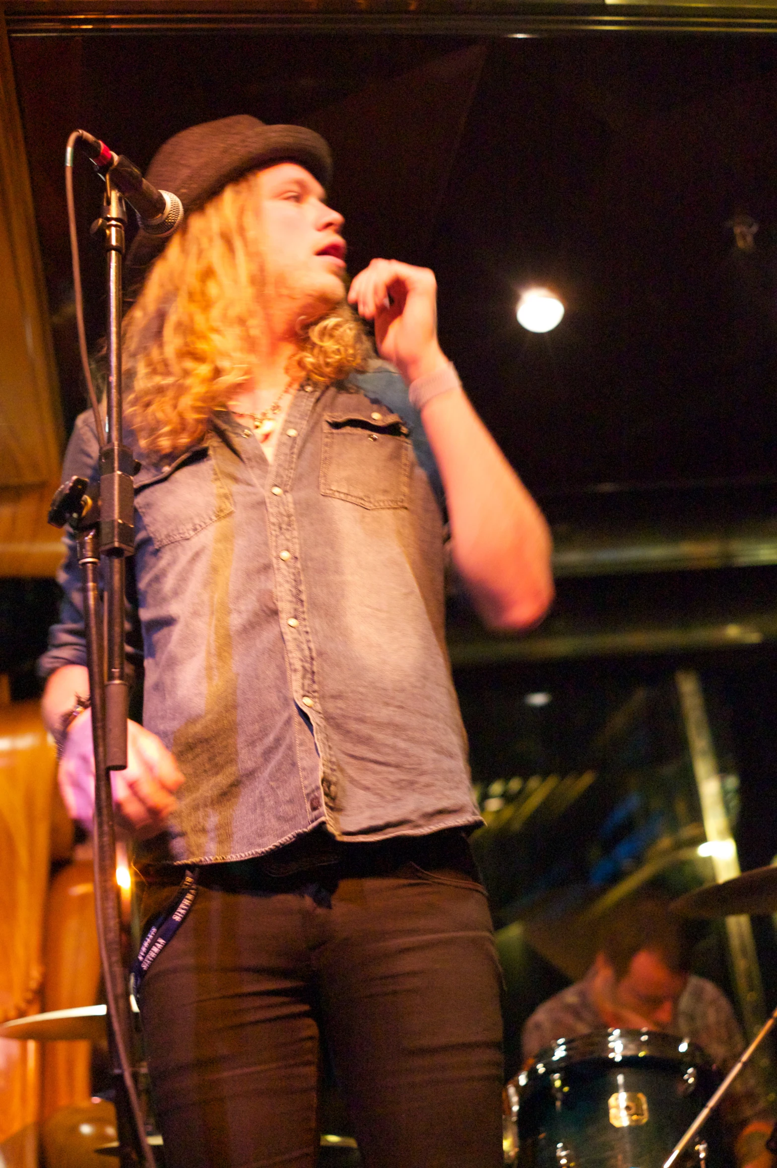 a man in a vest singing on stage