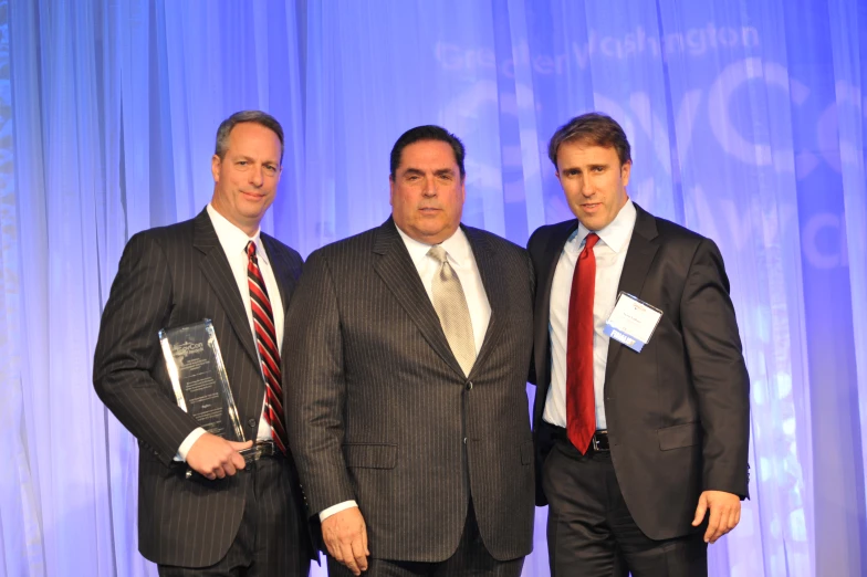 three men pose together before accepting an award