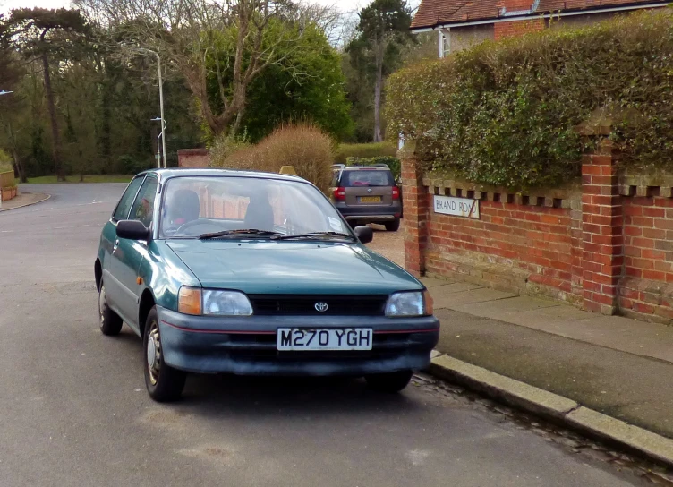 a small blue car parked on the side of the road