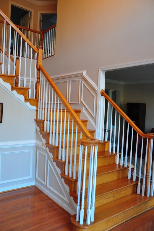 a hallway with a large wooden banister and white railing