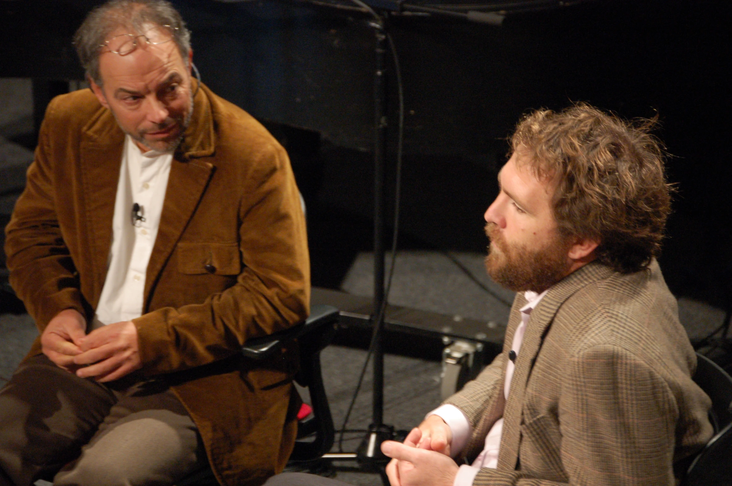 two men are having a conversation while one man sits down