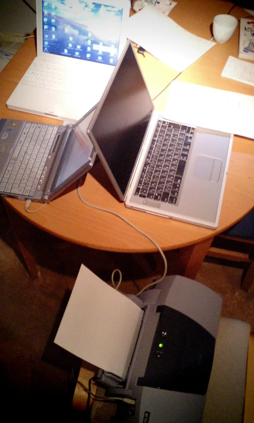 three laptops are sitting on a round wooden table