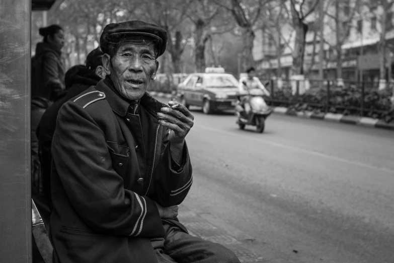 an old man sitting on a bench while smoking