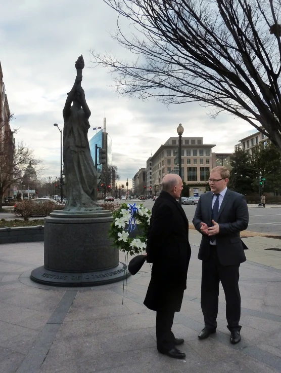 two men in suits standing by a statue