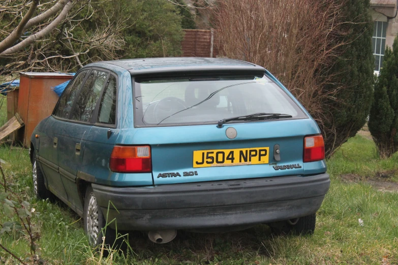 there is a blue car that has been left in the yard